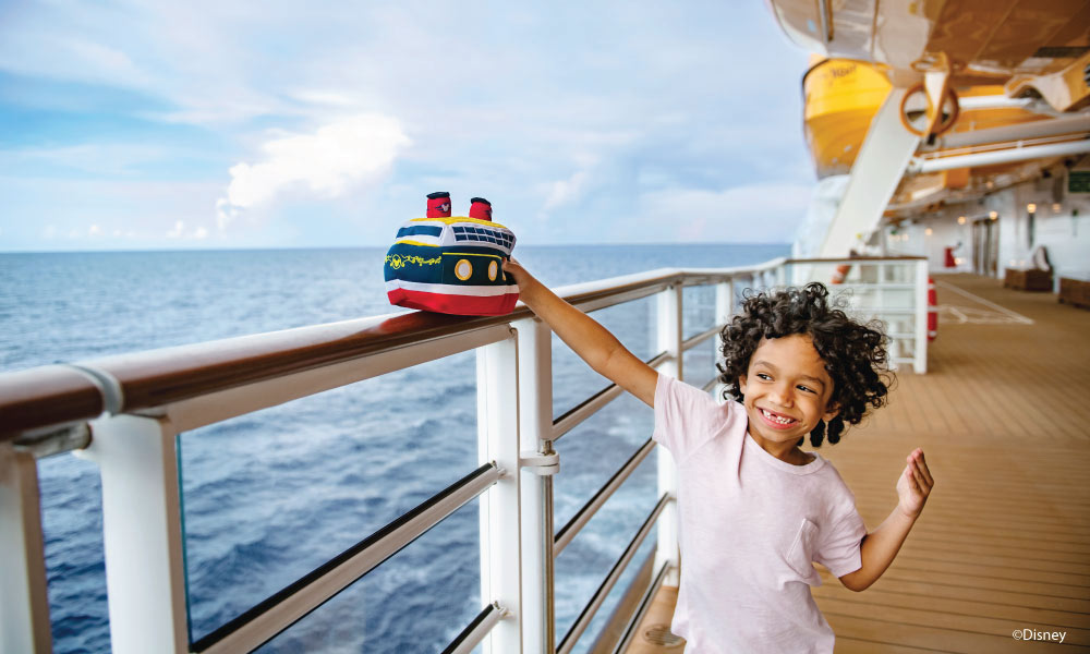 Little Boy playing with a cruise plush toy on the guard rail of a cruise ship