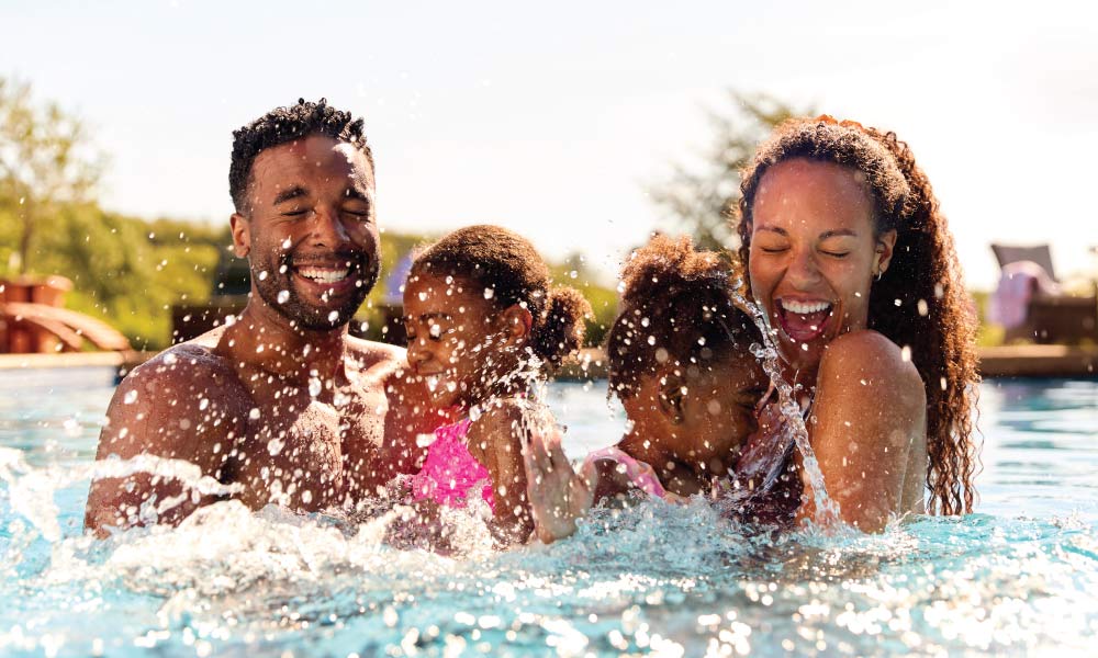 Family with young kids splashing and laughing in the pool