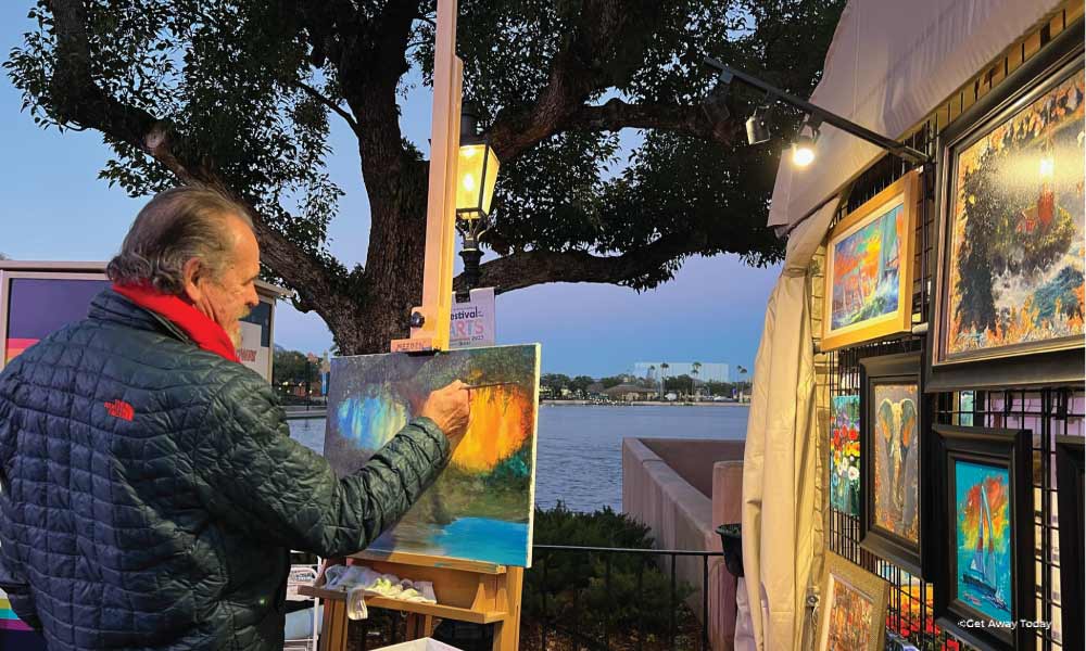 Artist painting an outdoor scene at EPCOT's Festival of the Arts