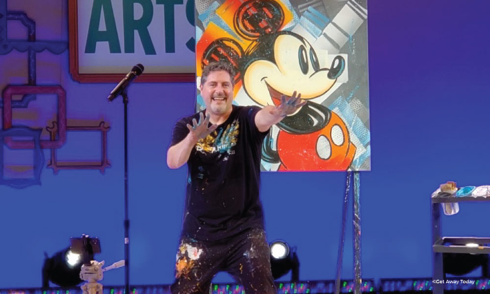 Artist posing in front of a modern Mickey painting on stage