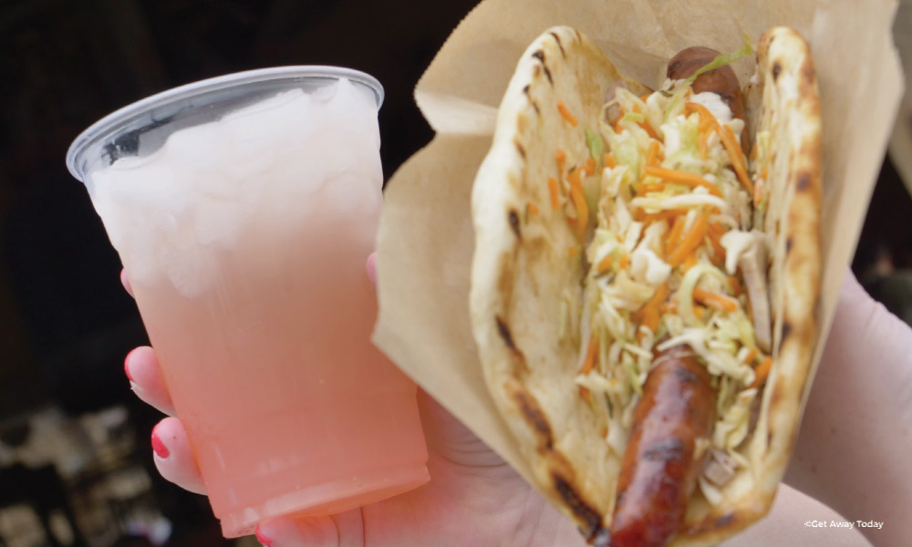 Ronto wrap with coleslaw and pink drink held up