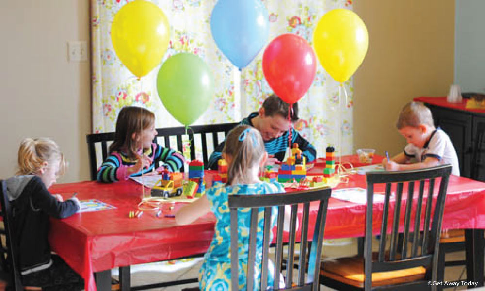 Kids sitting at a decorated table with balloons coloring