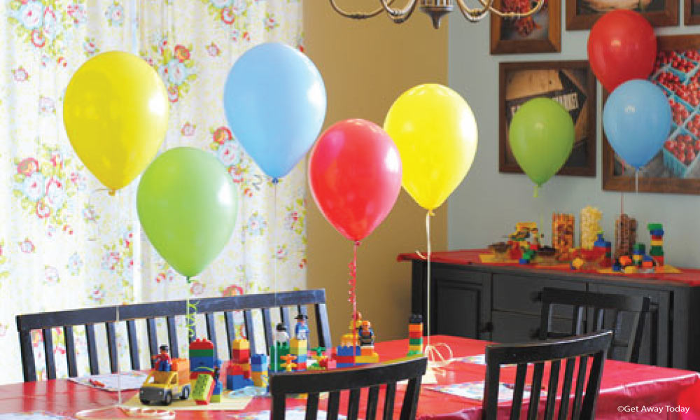 Table with red tablecloth, primary color balloons, and legos as decor in a dining room