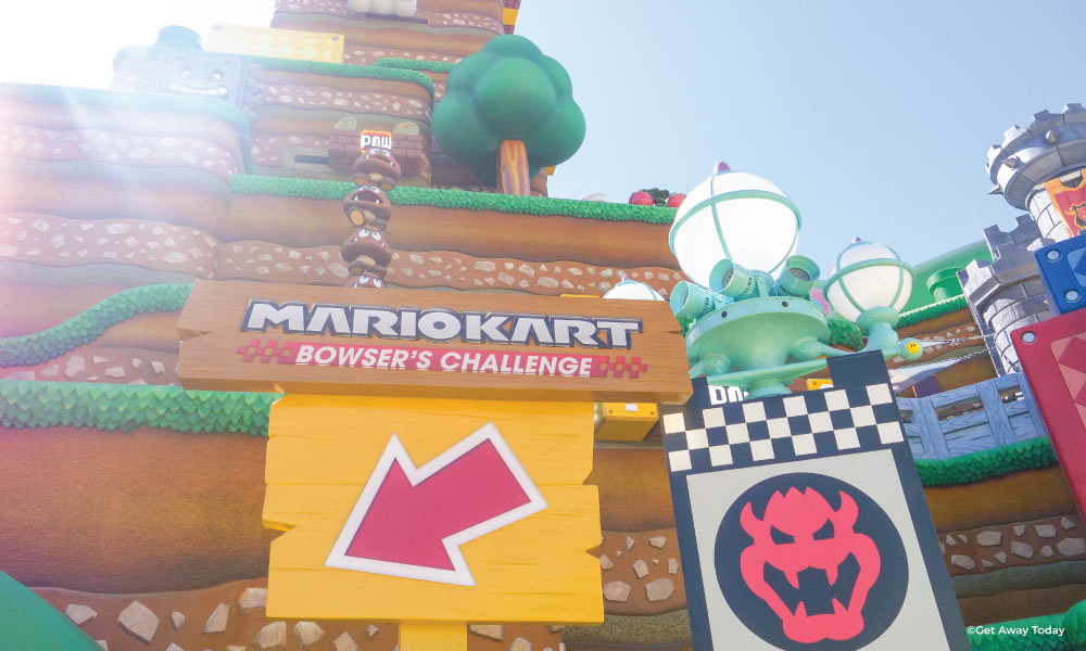 Mario Kart Bowsers Challenge wooden sign at ride entrance with bowser symbol