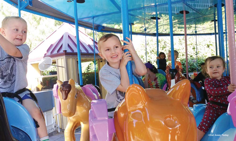 Three toddlers riding a carousel