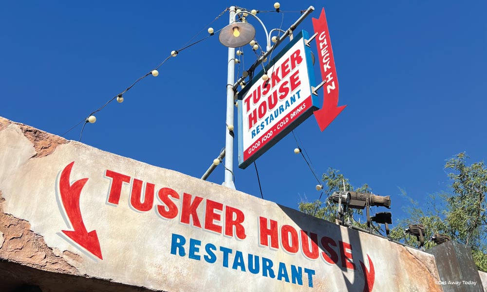 Tusker House Restaurant entrance with bold red and blue letters on a cement looking building