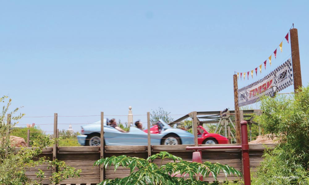 Blue and Red car crossing the finish line at Radiator Springs Racers