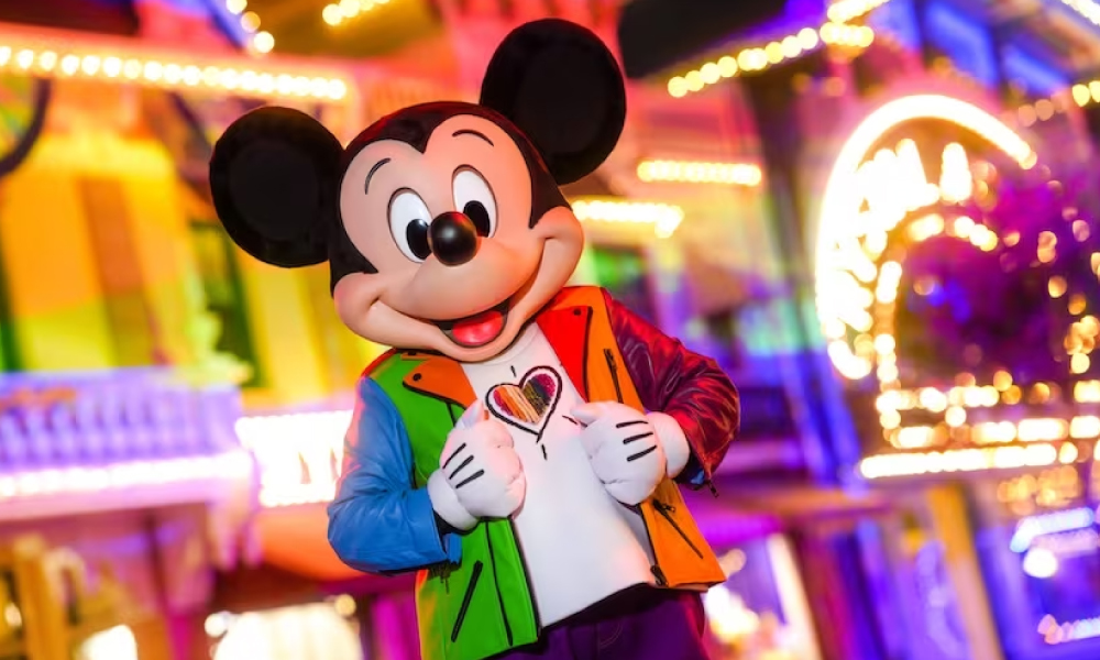 Mickey Mouse at Disneyland dressed in Pride clothes with rainbow pattern and rainbow lights on Main Street USA