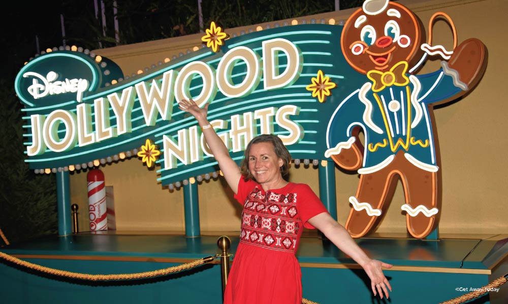 Woman posing in front of the neon Jollywood sign with a gingerbread