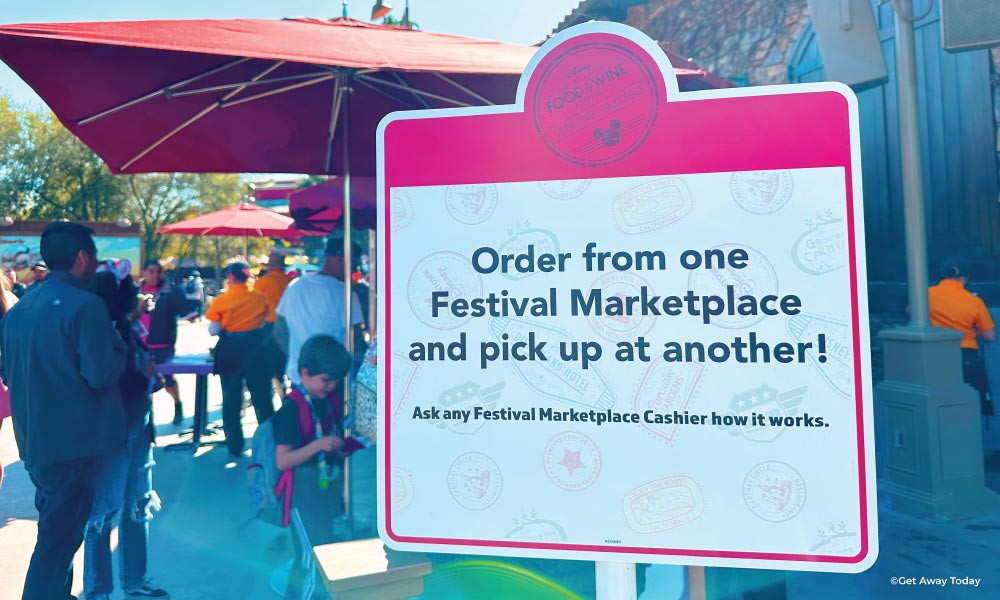 Sign directing Disneyland Guests that they can pick up their Food and Wine Festival food at any booth