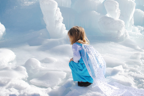 Little girl dressed as elsa squatting at the ice castles