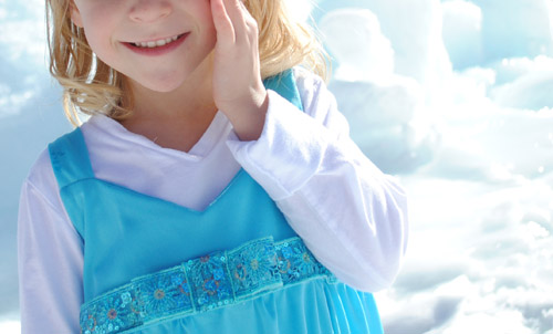 Close up of the top of an Elsa dress with a child's hand on her face