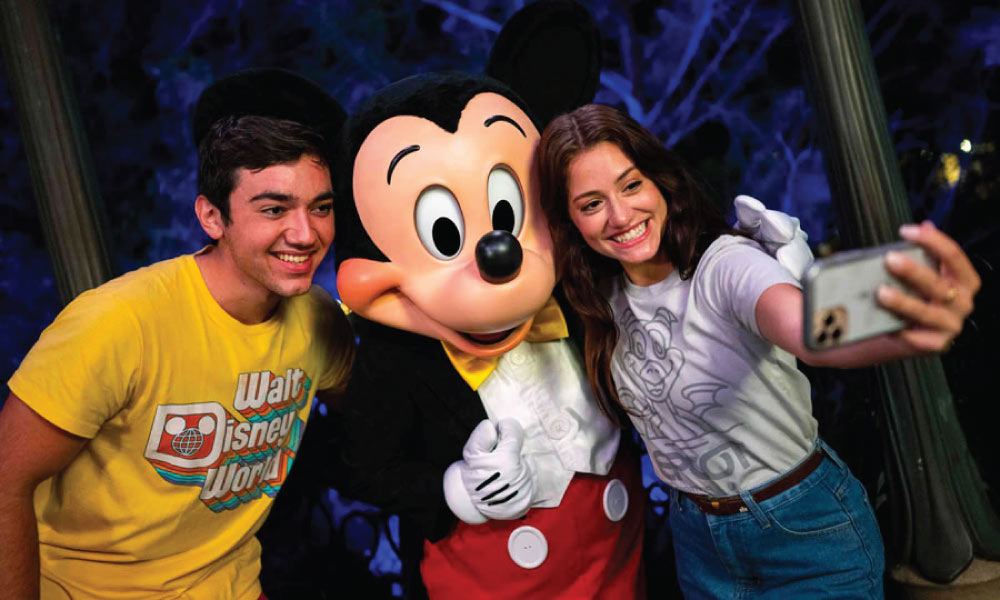 Young man and woman posing taking a selfie with Mickey