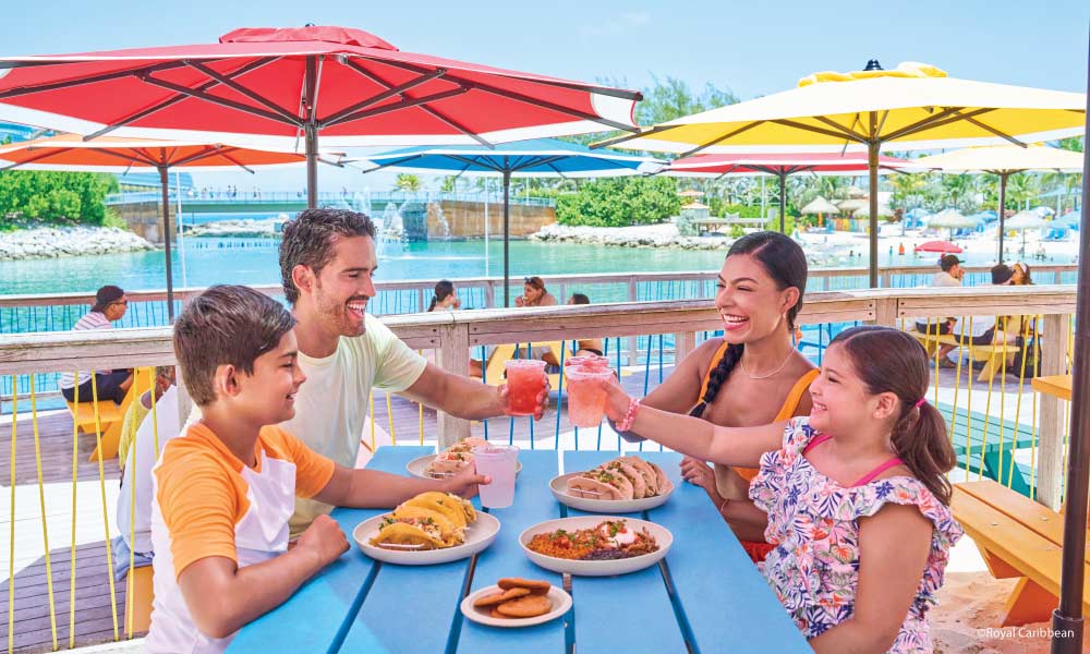 Mom and Dad Cheering drinks with kids eating and colorful umbrellas in the background