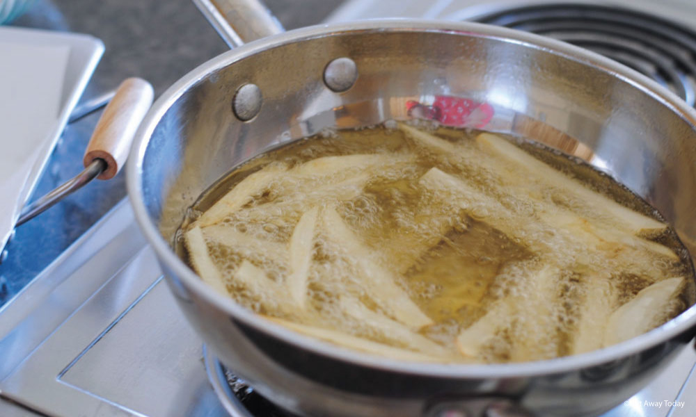 Frying potatoes in boiling oil to make fries in a silver pan