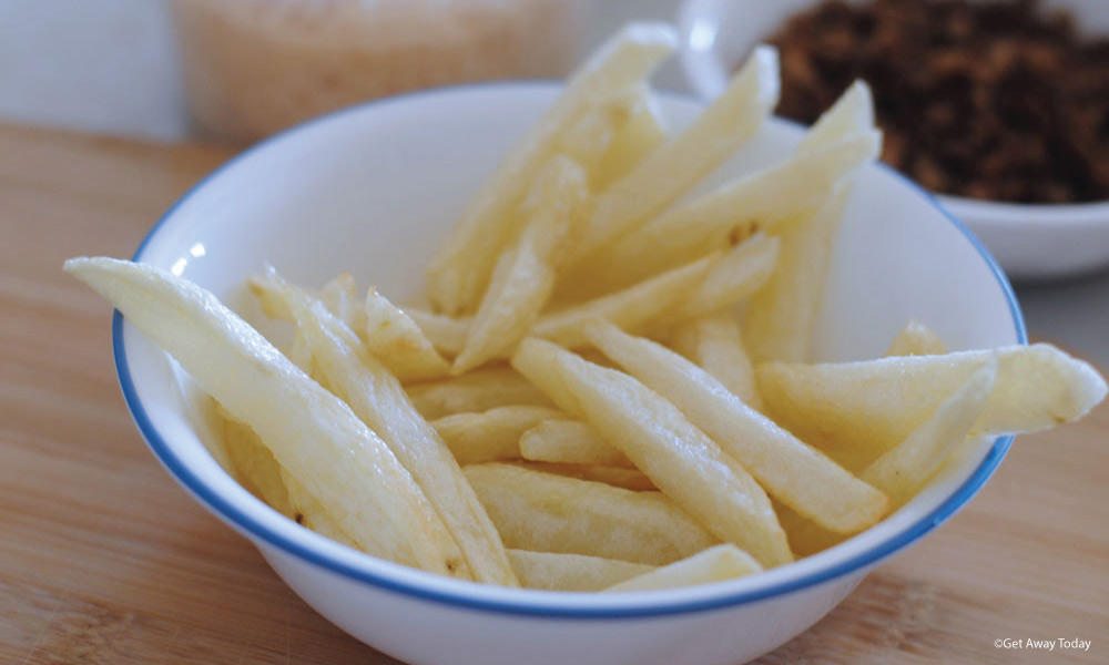 French fries in a white bowl with a blue rim