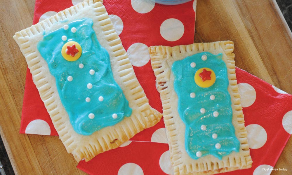 two homemade pop tarts with blue frosting, decorating pearls and a candy pixar ball