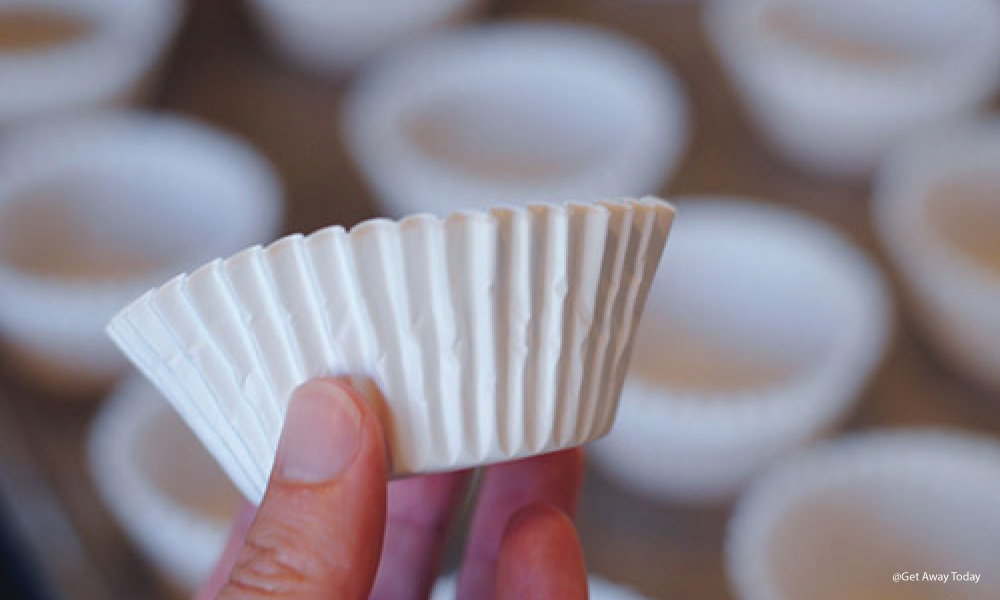 Hand holding up a white, empty baking cup