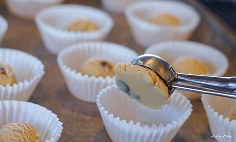 Cookie scoop dropping dough into an empty baking cup