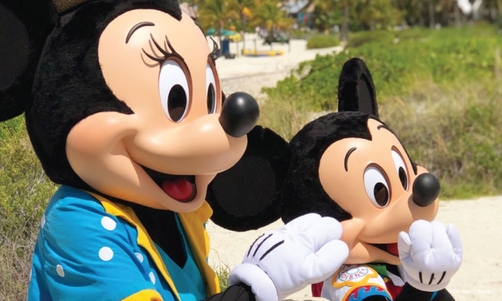 Mickey and Minnie greeting guests on a beach